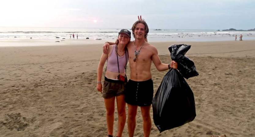 Two students pick up trash on a beach as part of a service project. 